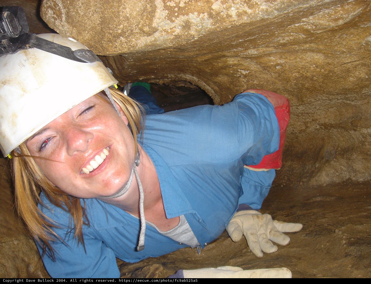 Smiling Caver Squeezes Through Tight Underground Passage