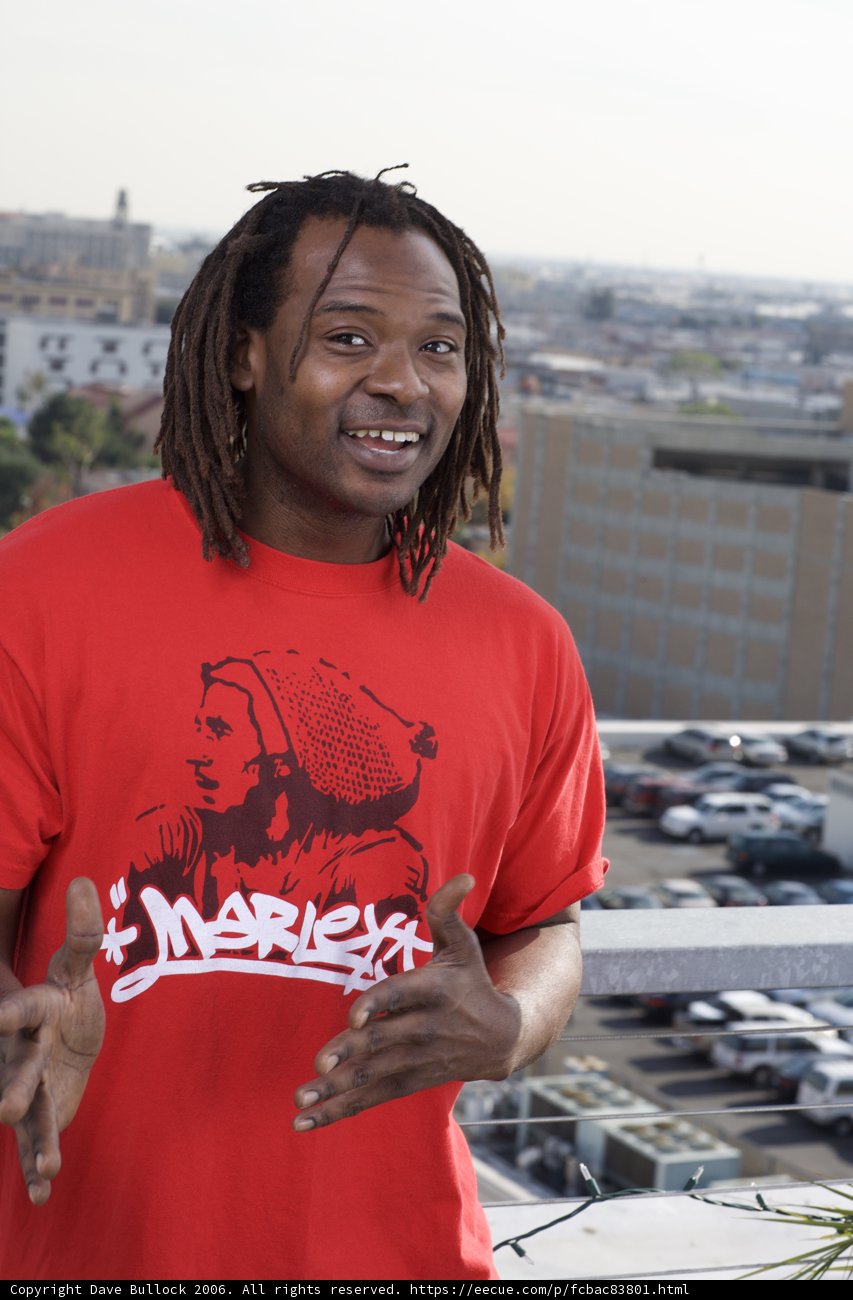 Red Shirted Man Poses with Vehicles in Parking Lot
