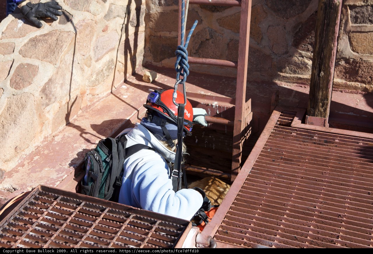 Man in Helmet and Harness Climbing Ladder