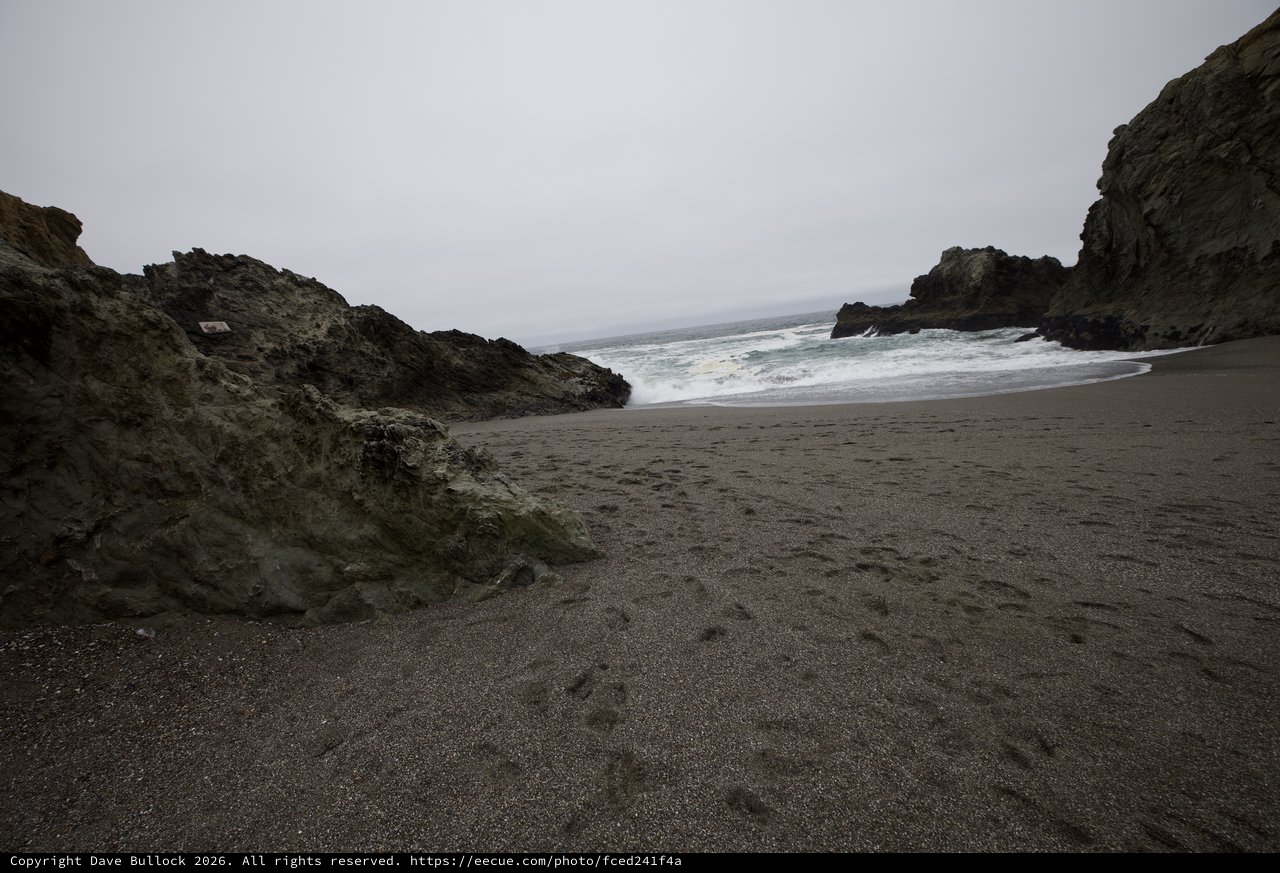 Rugged Cove Beach with Dark Sand and Crashing Waves