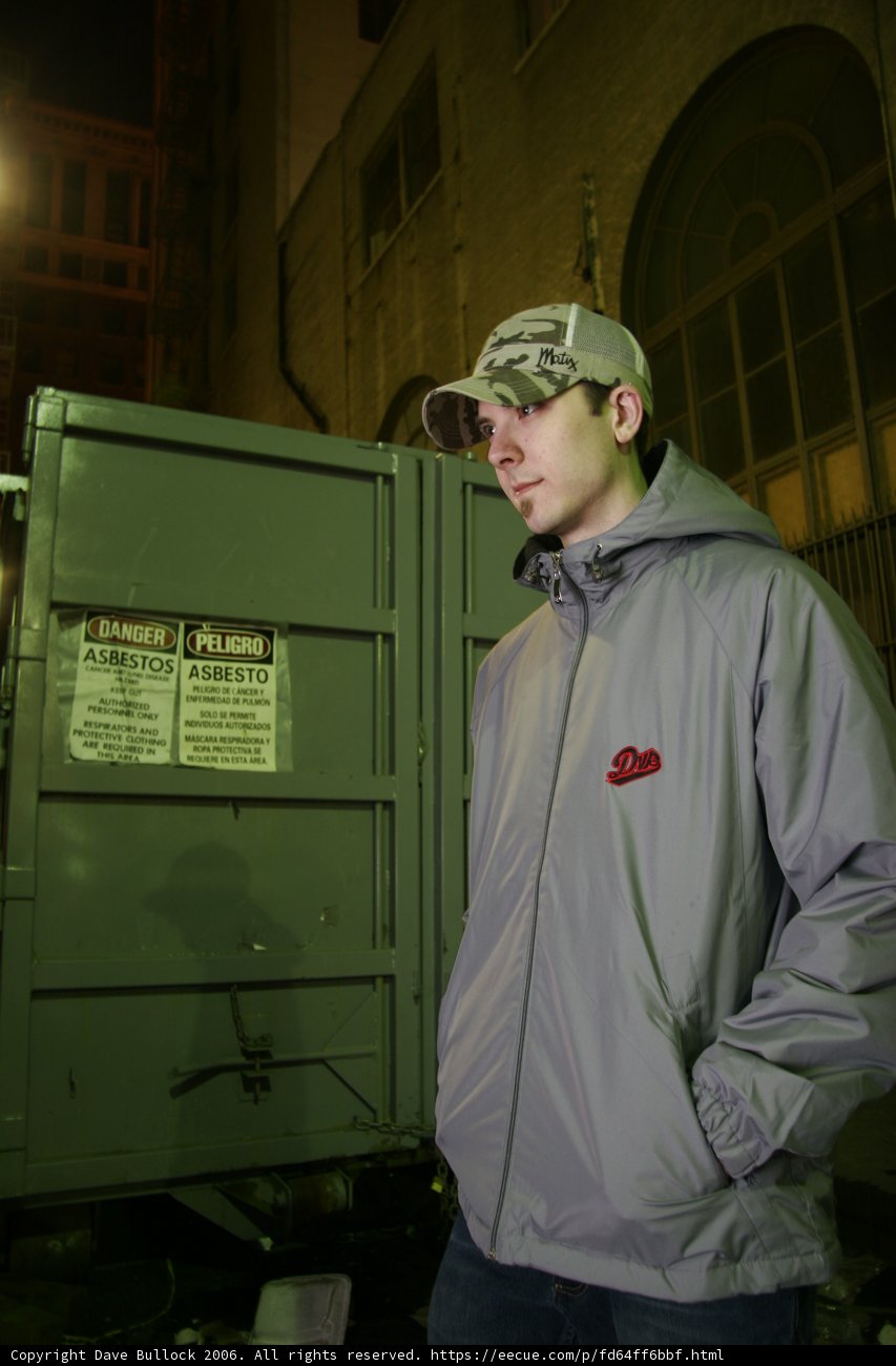 Grey Jacketed Man Stands Tall in front of a Building