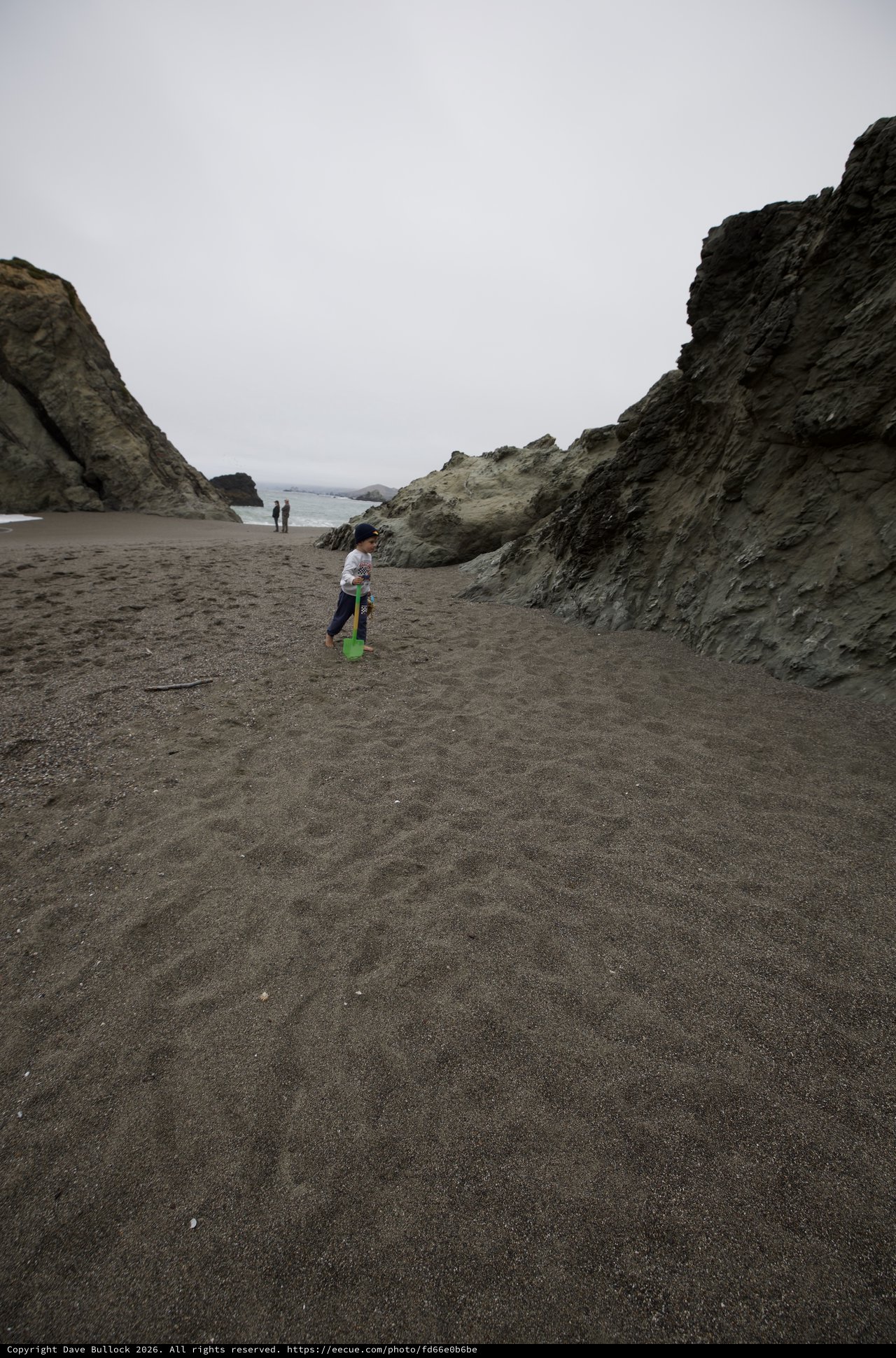Young Explorer with Shovel on Dark Sand Beach