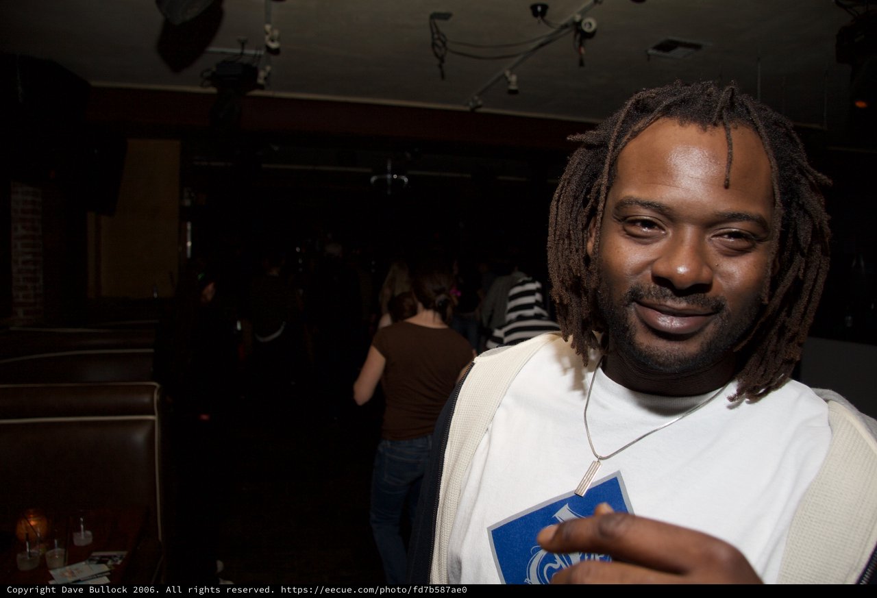 Man Smiling at Nightclub Venue with Dreadlocks