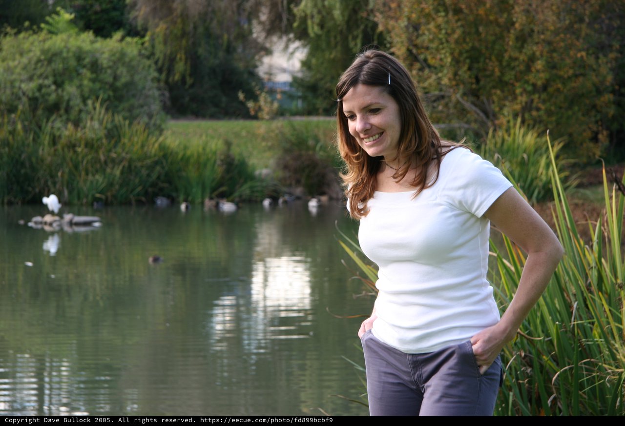 Woman Smiling by a Tranquil Park Pond