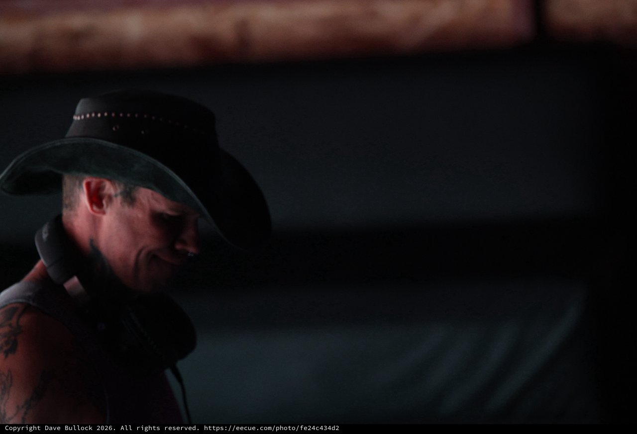 Tattooed Performer in Black Cowboy Hat Under Stage Lights