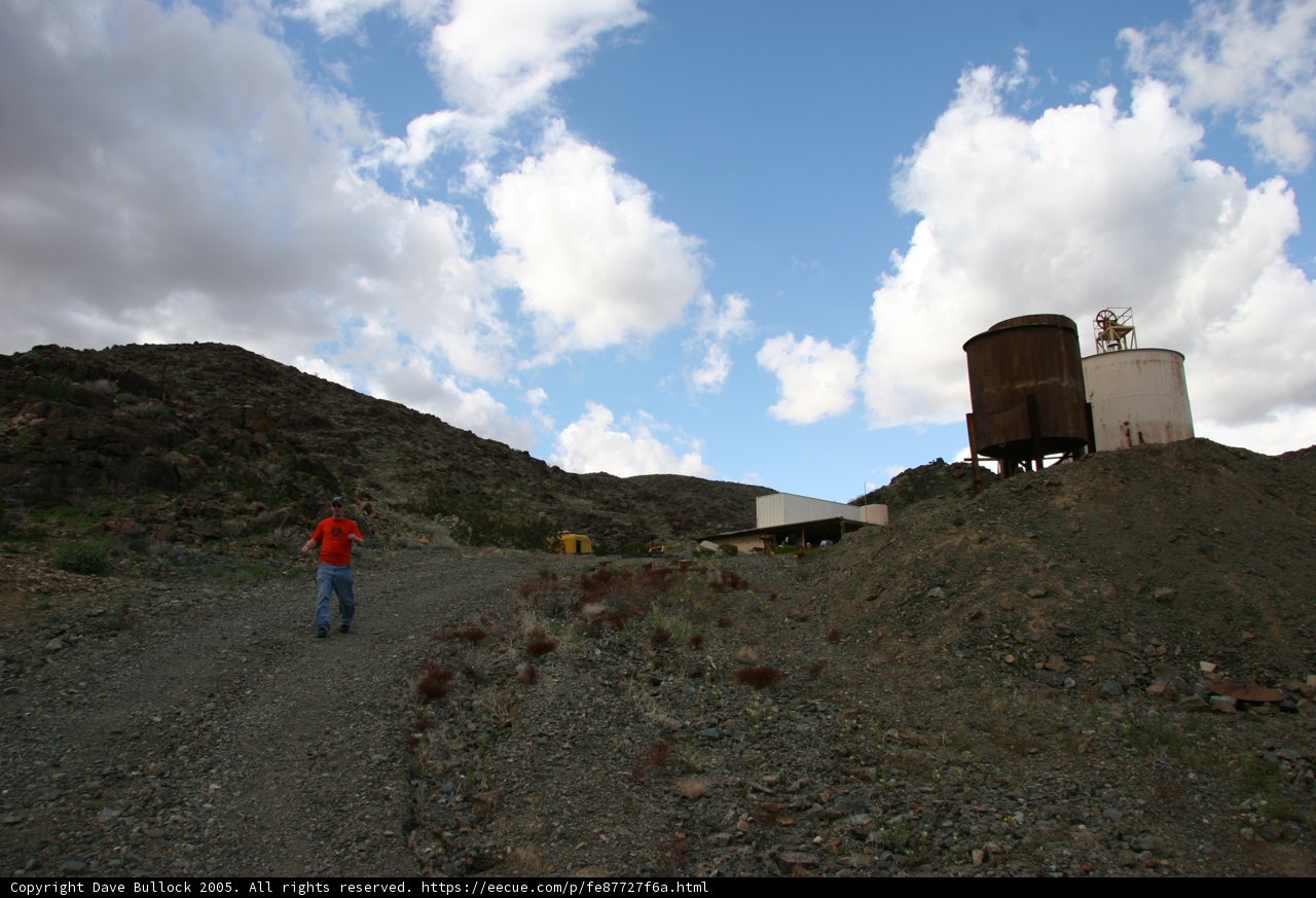 Man with Tank Walking Down Dirt Road