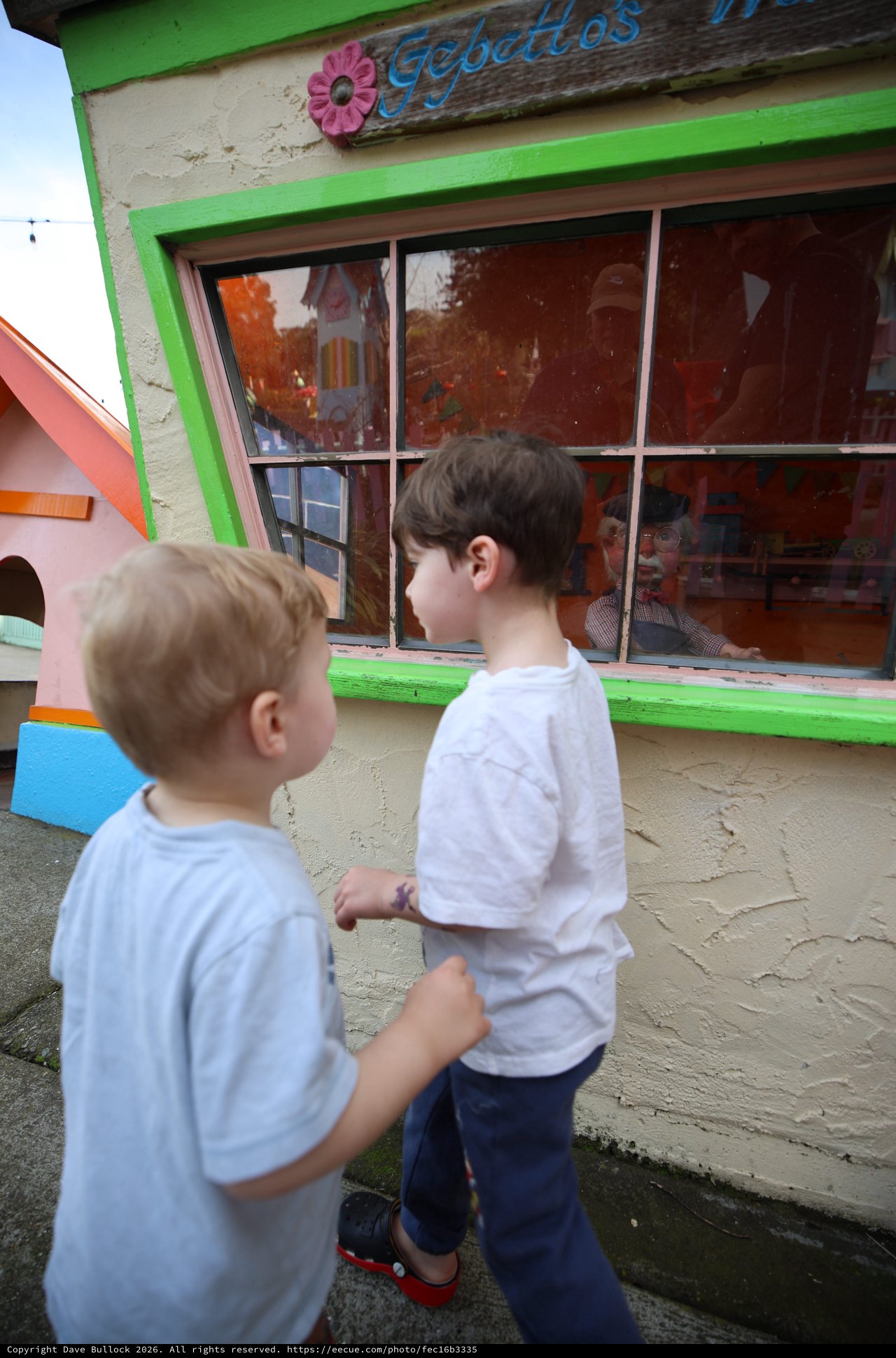 Two Brothers Peering into Colorful Playhouse Window