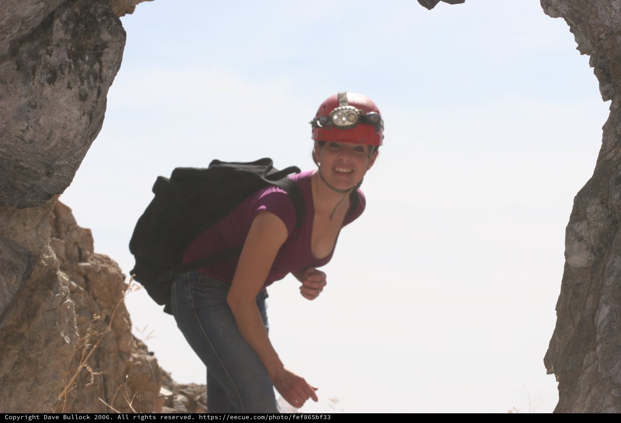 Cave Explorer Peering Through Rocky Desert Opening
