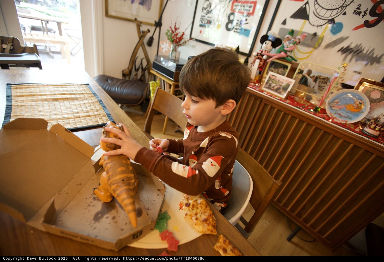 Child Enjoying Christmas Pizza with Dinosaur Toy