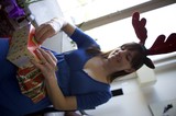 Joyful Woman Unwrapping Christmas Gifts in Reindeer Antlers