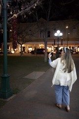 Woman Photographing Plaza Decorations at Night in Santa Fe