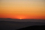 Last Light: Sun Dissolves Behind Distant Mountain Ridges