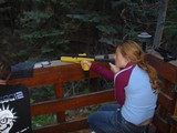 Young Woman Aiming Yellow Air Pistol on Wooden Deck