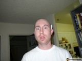 Bald Headed Man Captures Selfie by Bookshelf