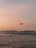 Helicopter Flying Over San Francisco Bay Caption: A stunning view from above as a helicopter soars over the ocean beside a boat enjoying the waters of San Francisco Bay at sunset.