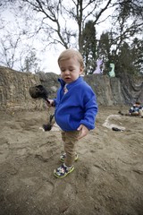Toddler with Brush at Sandy Play Area