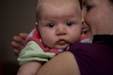 Curious Baby Gazes Forward Over Parent's Shoulder