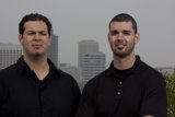 Two Happy Men in Black Shirts by Skyscraper