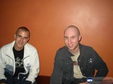Two Men Sitting in Front of an Orange Wall