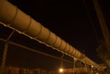 Towering Pipeline and Fence at Night