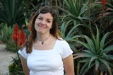 Woman Smiling Amid Desert Succulents and Aloe Blooms