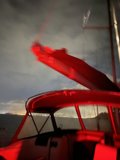 Red Light Illuminates Sailboat in the Bay