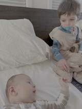Baby and Toddler Siblings on White Bedding