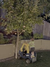 Child Playing with Toy Car in Backyard