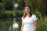 Young Woman Smiling by a Tranquil Park Pond