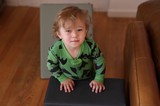 Toddler in Green Dinosaur Pajamas at Home