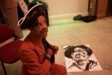 Man in Suit and Hat with Artwork on Hardwood Floor