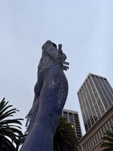 Towering Goddess Statue Against Urban Skyline
