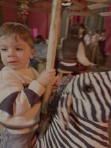 Child Riding Carousel at Indoor Amusement Park