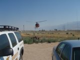 Helicopter in Flight Over a Field with a Car in the Background