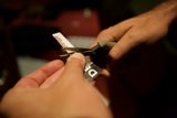 Precise paper cutting Caption: A person's fingers and hand skillfully wield scissors to cut through a piece of paper with precision. In the background, a credit card and text can be seen on a table. Photograph taken in 2008 at pre defcon.