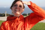 Smiling Woman Shielding Eyes in Orange Jacket