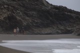 Figures Walking Along Rocky Coastal Beach