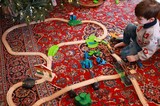 Child Playing with Wooden Train Set Under Christmas Tree