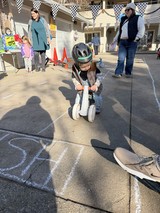 Young Child Racing on Scooter at Backyard Party