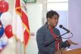 Woman Addressing Crowd with Flag in Background