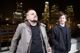 Two Men In Overcoats Against Metropolis Skyline