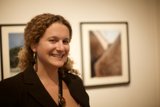 Curly-haired Woman Smiling in Front of Wall