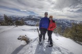 Summit Smiles: Couple Atop Snow-Covered Mountain Peak