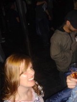 Young Woman Smiling at a Nighttime Social Gathering