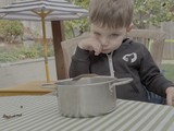 Young Boy Eating Outdoors at Garden Table
