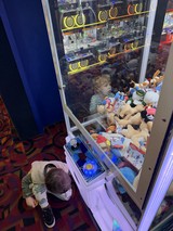 Child Playing Claw Machine Game at Arcade
