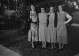 Four women in beautiful dresses posing for a photo