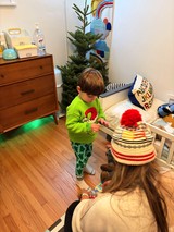 Young Child Examining Art or Toy by Christmas Tree