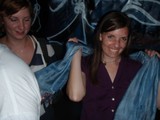 Two Women Holding Blue Fabric at Nighttime Event