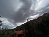Red House Sheltered by Majestic Mountains and Stormy Sky